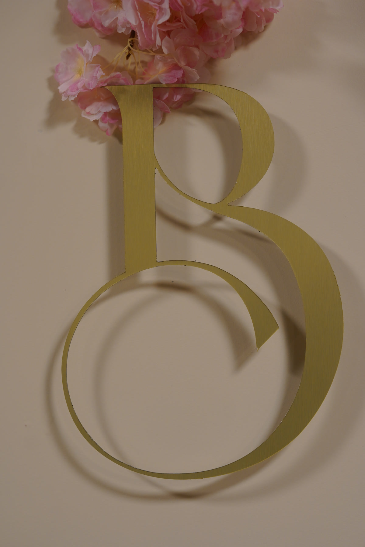 Gold "B" letterform with cherry blossom branding detail