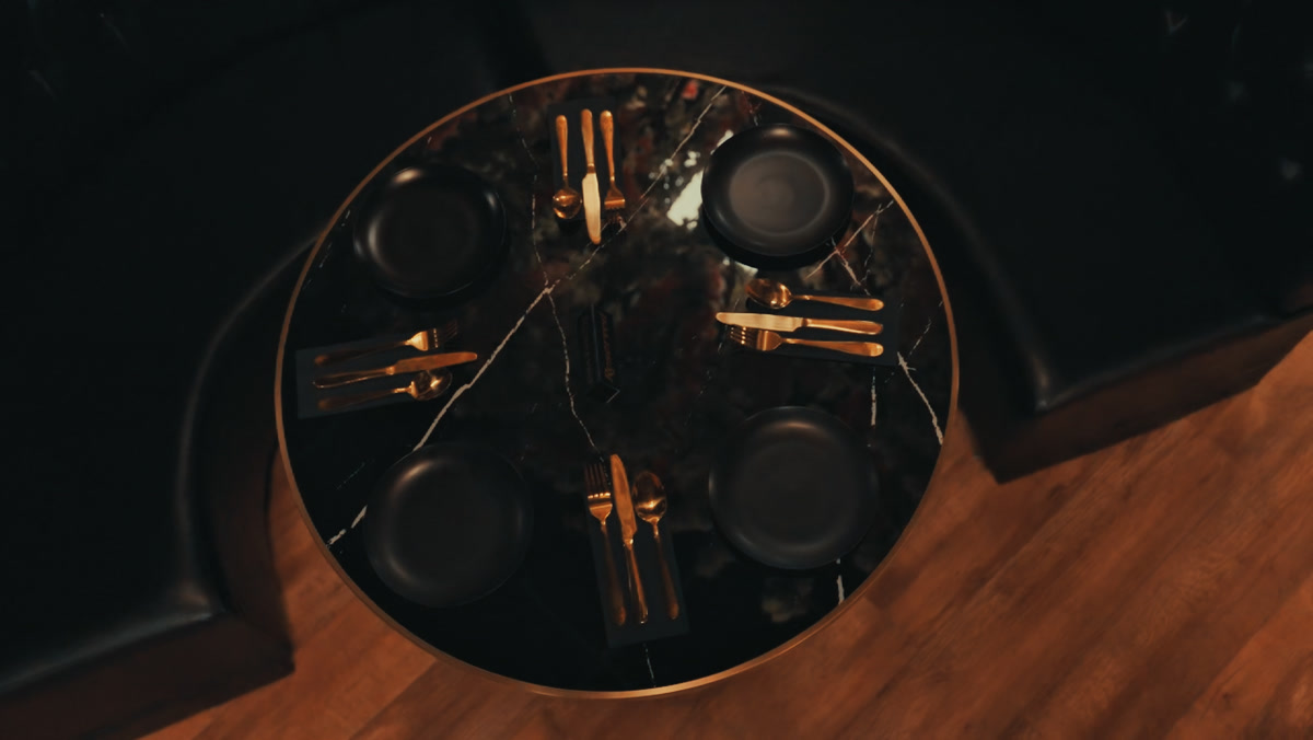 Overhead view of a marble table set with gold cutlery and dark plates